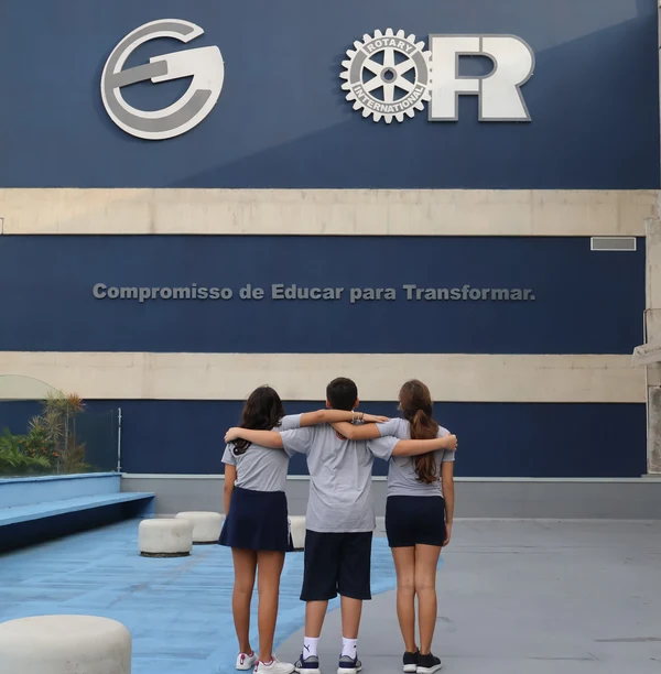 Três estudantes do Colégio Eduardo Gomes em frente à escola